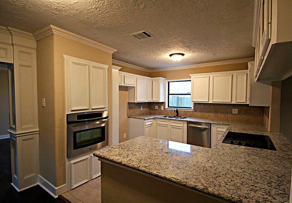 Mid-sized transitional u-shaped ceramic tile and beige floor enclosed kitchen photo in Houston with a double-bowl sink, recessed-panel cabinets, white cabinets, granite countertops, beige backsplash, ceramic backsplash, stainless steel appliances and a peninsula
