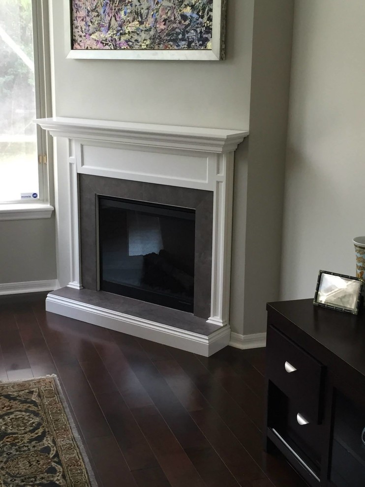 Photo of a mid-sized traditional formal enclosed living room in Miami with grey walls, dark hardwood floors, a corner fireplace, a wood fireplace surround, no tv and brown floor.