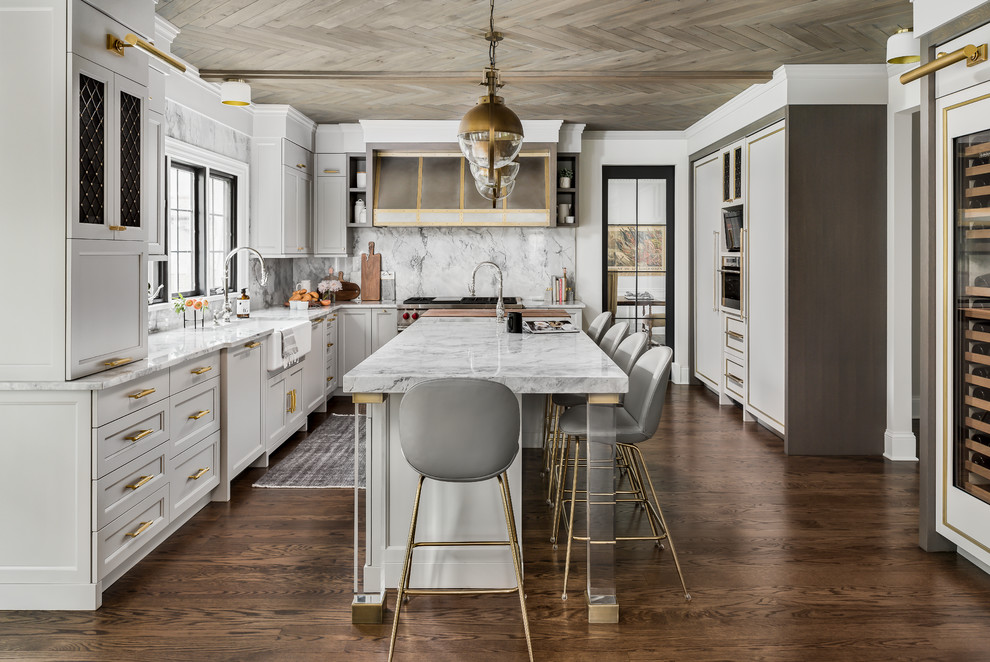 Enclosed kitchen - mid-sized transitional medium tone wood floor and brown floor enclosed kitchen idea in Chicago with a farmhouse sink, recessed-panel cabinets, gray cabinets, quartzite countertops, gray backsplash, stone slab backsplash, paneled appliances, an island and gray countertops