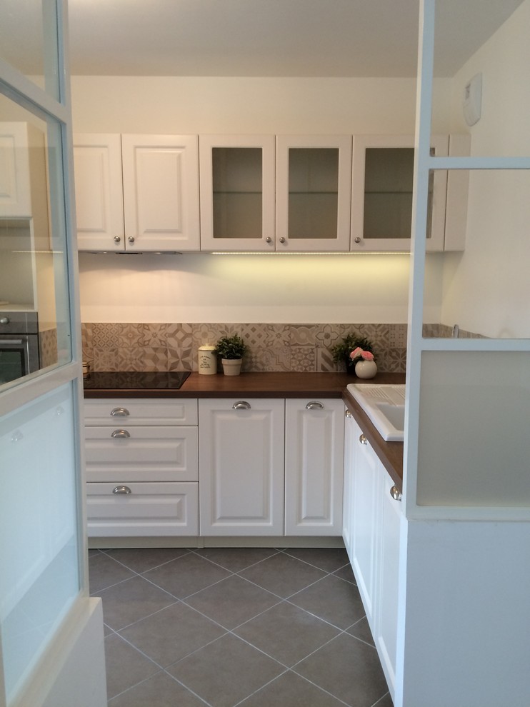 Small traditional l-shaped open plan kitchen in Lyon with an undermount sink, wood benchtops, beige splashback, cement tile splashback, stainless steel appliances, ceramic floors, no island, beaded inset cabinets and stainless steel cabinets.