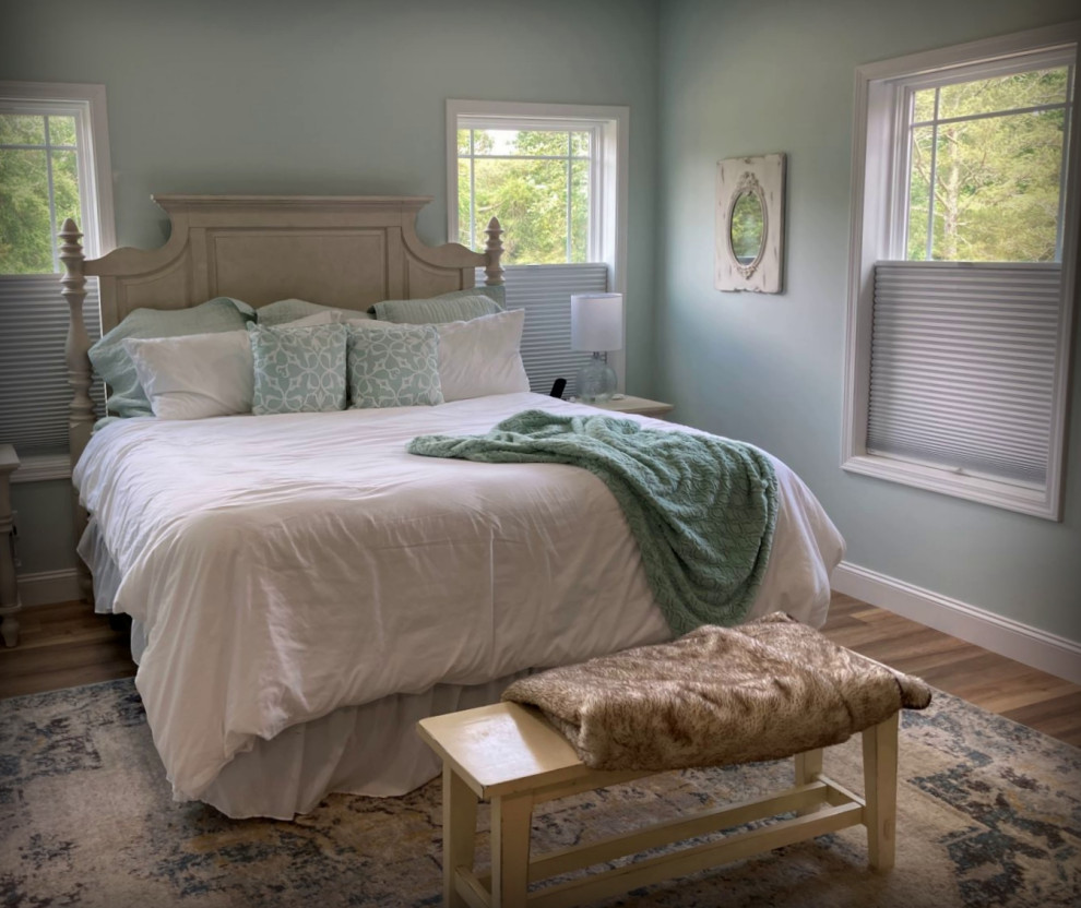 Großes Country Hauptschlafzimmer mit blauer Wandfarbe, Laminat und braunem Boden in Sonstige