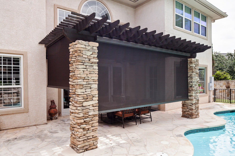 Example of a mid-sized classic backyard stone patio design in Austin with an awning