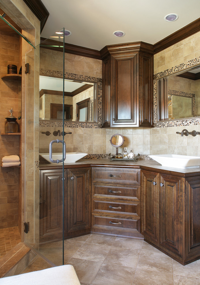 Mid-sized eclectic master bathroom in Newark with a vessel sink, furniture-like cabinets, dark wood cabinets, tile benchtops, an alcove tub, an alcove shower, a one-piece toilet, beige tile, stone slab, beige walls and porcelain floors.
