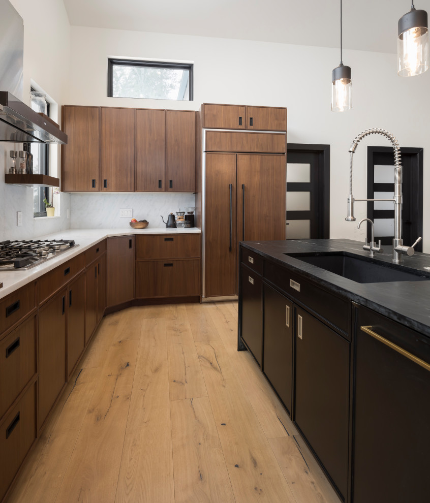 Photo of a mid-sized industrial l-shaped open plan kitchen in Denver with shaker cabinets, medium wood cabinets, marble benchtops, panelled appliances, light hardwood floors, with island, brown floor and multi-coloured benchtop.