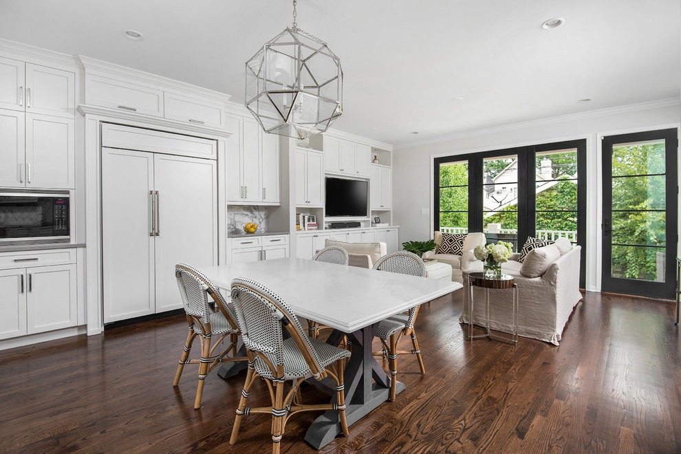 Inspiration for a mid-sized transitional l-shaped medium tone wood floor open concept kitchen remodel in Chicago with an undermount sink, recessed-panel cabinets, white cabinets, solid surface countertops, white backsplash, stone slab backsplash, white appliances and an island