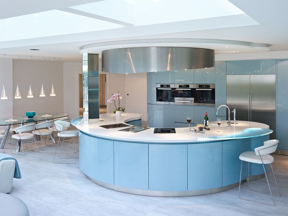 Photo of an expansive modern u-shaped kitchen/diner in London with an integrated sink, flat-panel cabinets, blue cabinets, composite countertops, blue splashback, glass sheet splashback, stainless steel appliances, marble flooring and an island.