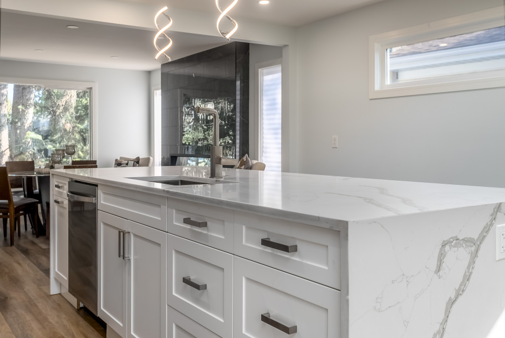 Example of a transitional kitchen design in Edmonton with shaker cabinets, white cabinets, quartzite countertops, gray backsplash, cement tile backsplash, stainless steel appliances, an island and white countertops