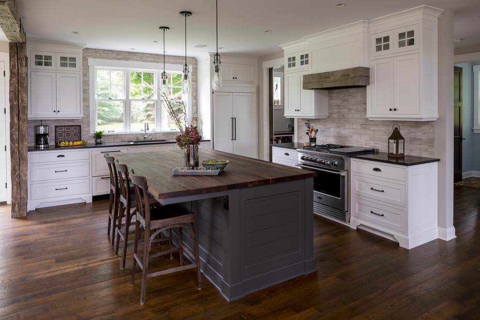 Mid-sized beach style l-shaped kitchen in Minneapolis with an undermount sink, flat-panel cabinets, white cabinets, granite benchtops, ceramic splashback, panelled appliances, dark hardwood floors, with island and brown floor.