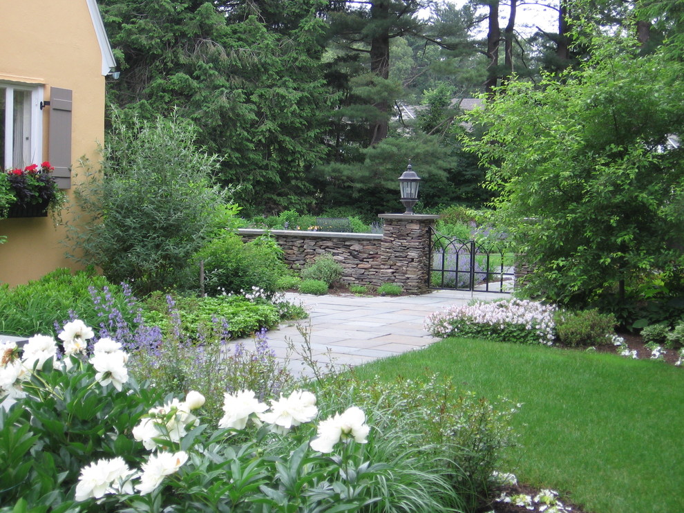 Design ideas for a mid-sized backyard shaded formal garden for spring in Manchester with concrete pavers.