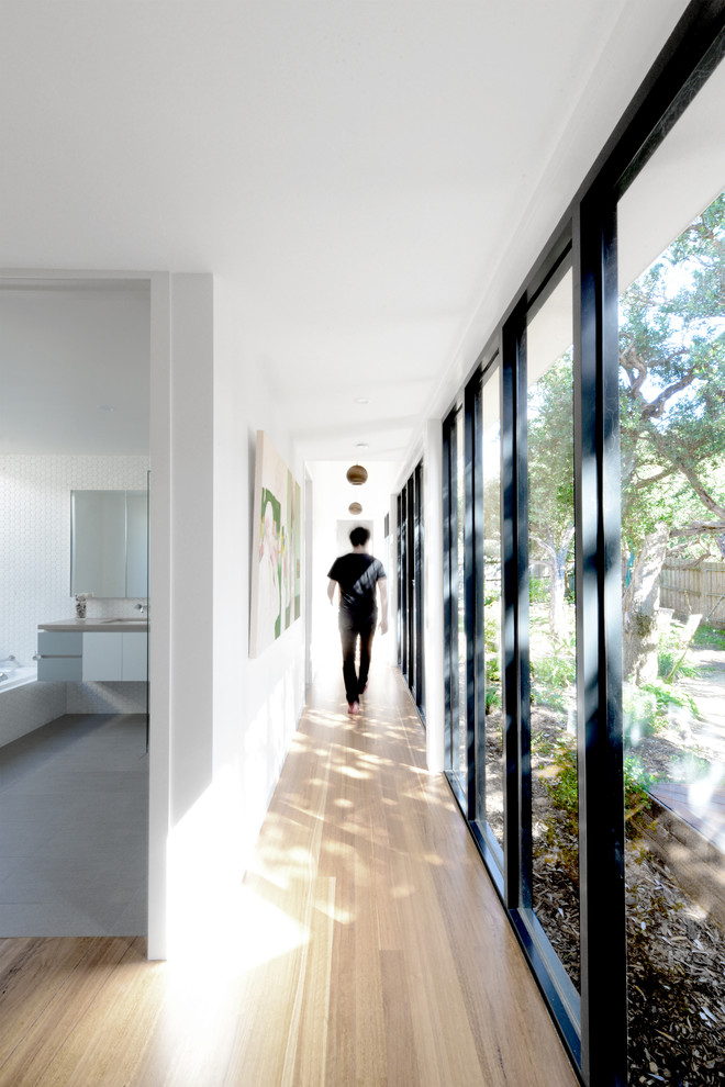 Modern hallway in Melbourne with white walls, light hardwood floors and beige floor.