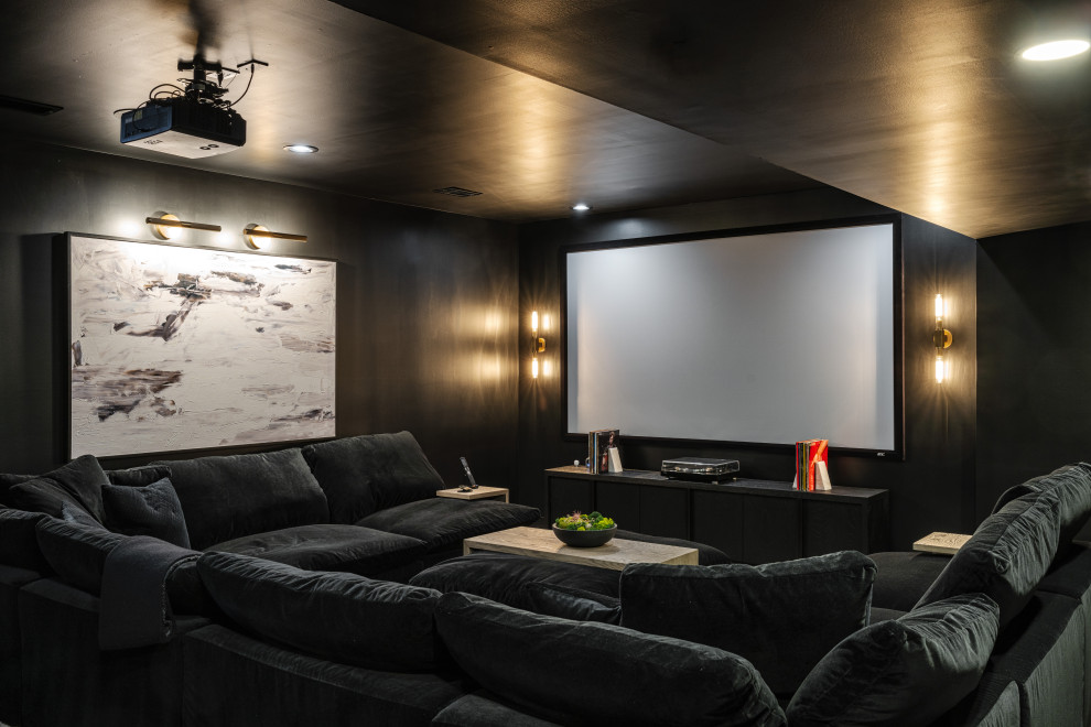 This is an example of a mid-sized modern open concept home theatre in Kansas City with black walls, carpet, a projector screen and black floor.