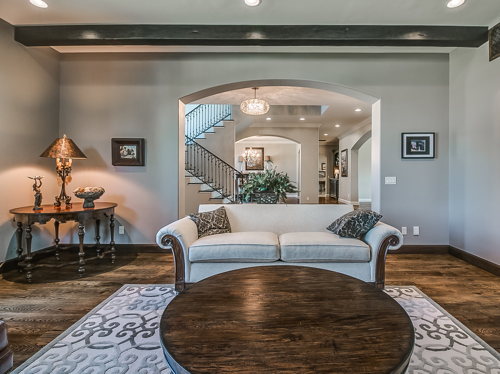 Inspiration for a mid-sized transitional enclosed family room in Oklahoma City with a library, grey walls, medium hardwood floors, a standard fireplace, a stone fireplace surround, a wall-mounted tv and brown floor.