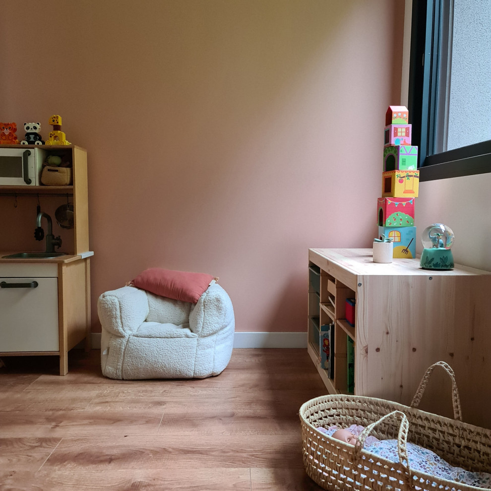 Inspiration pour une chambre de fille de 1 à 3 ans design avec un mur rose, sol en stratifié et un sol marron.