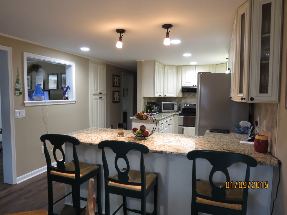 Example of a mid-sized u-shaped eat-in kitchen design in DC Metro with a double-bowl sink, raised-panel cabinets, white cabinets, granite countertops, beige backsplash, porcelain backsplash and stainless steel appliances
