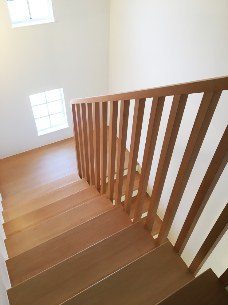 Ejemplo de escalera curva escandinava pequeña con escalones de madera y barandilla de madera