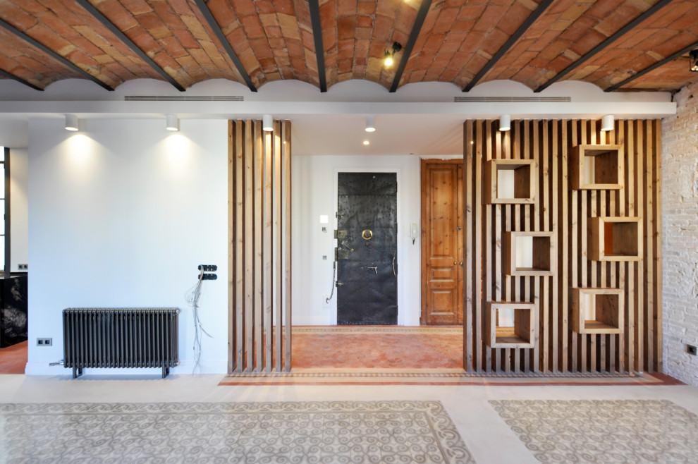 На фото: большая узкая прихожая в стиле модернизм с белыми стенами, полом из керамической плитки, одностворчатой входной дверью, металлической входной дверью, красным полом, сводчатым потолком и кирпичными стенами