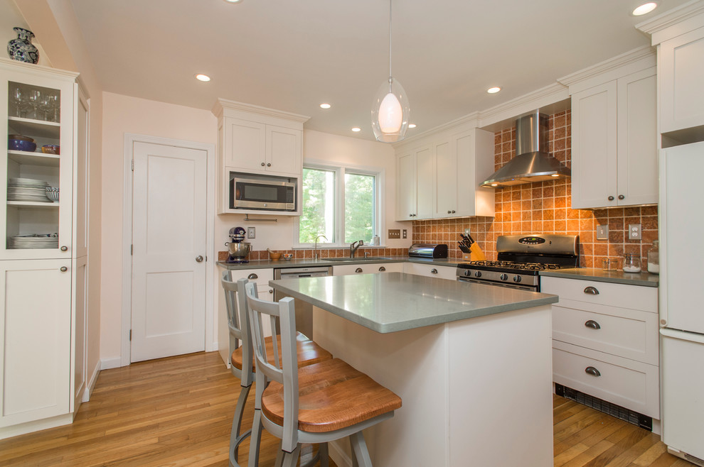 Photo of a mid-sized transitional l-shaped separate kitchen in Boston with an undermount sink, shaker cabinets, white cabinets, quartz benchtops, brown splashback, ceramic splashback, stainless steel appliances, light hardwood floors and with island.
