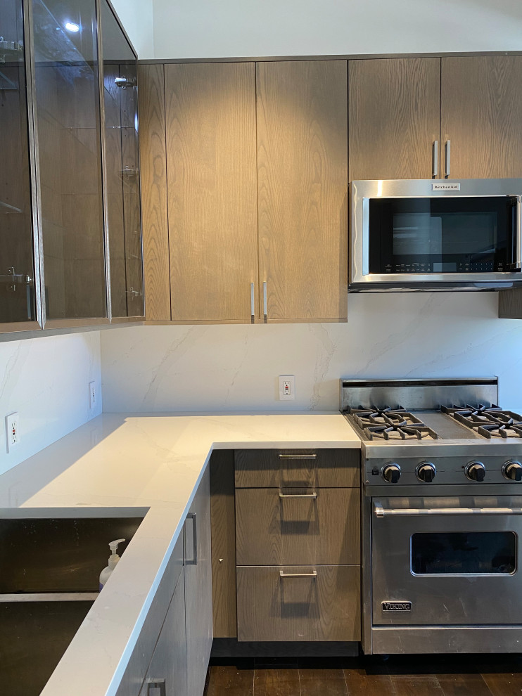 Photo of a mid-sized modern u-shaped kitchen in New York with an undermount sink, flat-panel cabinets, medium wood cabinets, quartz benchtops, yellow splashback, stainless steel appliances, dark hardwood floors, with island, brown floor and white benchtop.