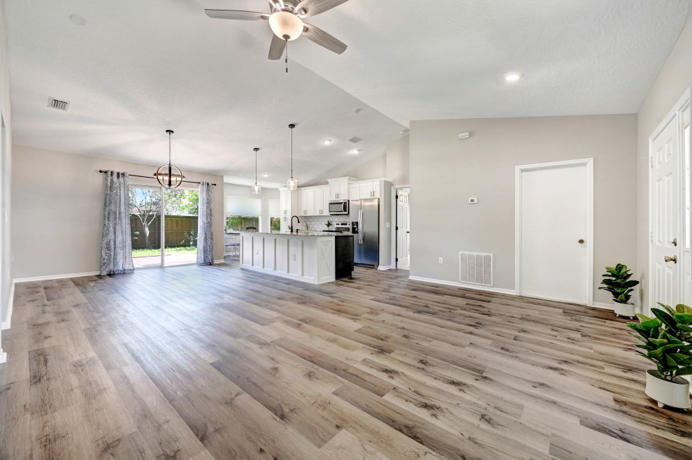 Photo of a mid-sized country open concept living room in Orlando with grey walls, vinyl floors, no fireplace, grey floor and vaulted.