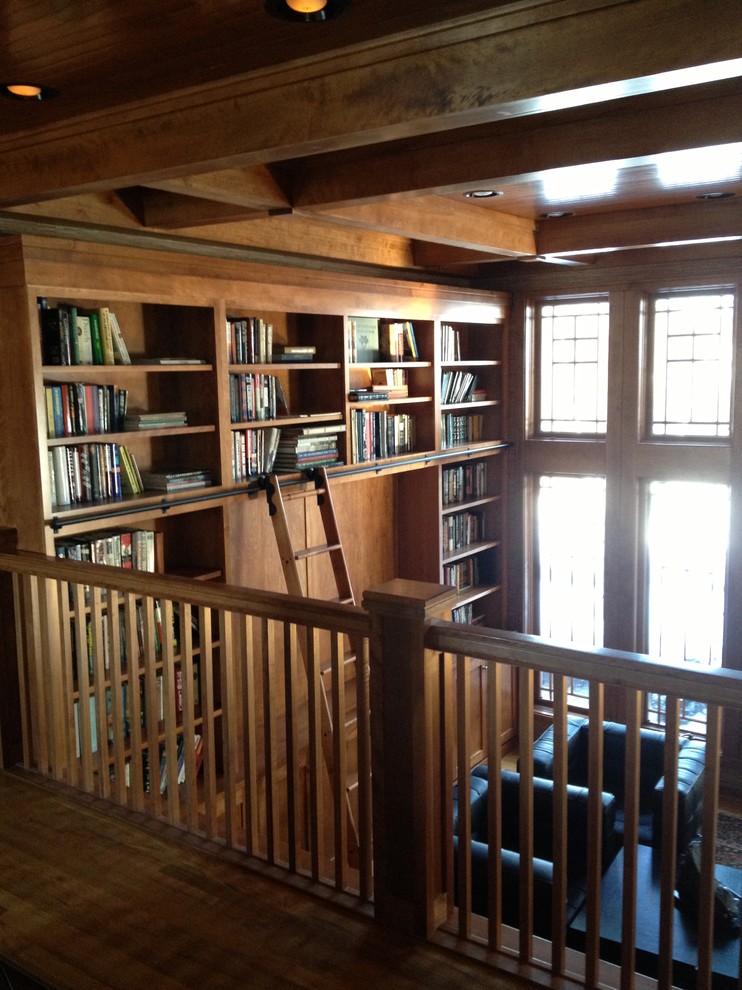 This is an example of a large traditional home office in Cleveland with a library, brown walls and dark hardwood floors.