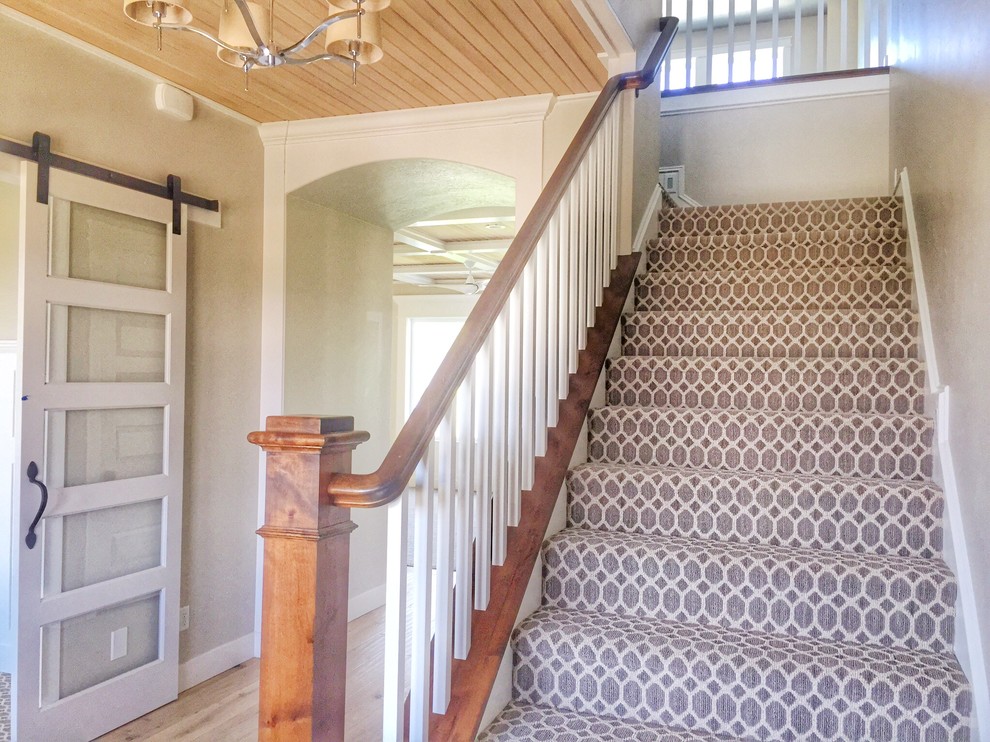 Mid-sized arts and crafts carpeted l-shaped staircase in Boise with carpet risers and wood railing.
