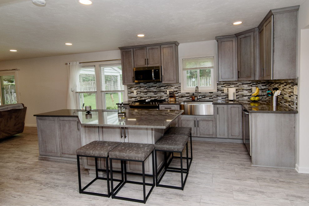Eat-in kitchen - large transitional u-shaped gray floor eat-in kitchen idea in Baltimore with a farmhouse sink, shaker cabinets, gray cabinets, quartz countertops, multicolored backsplash, glass tile backsplash, stainless steel appliances, an island and gray countertops