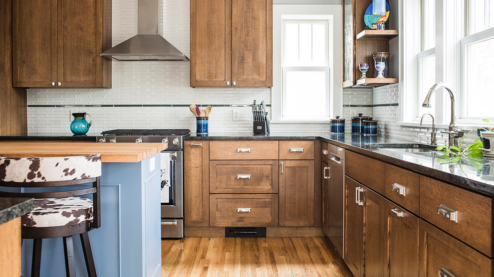 Inspiration for a mid-sized transitional l-shaped eat-in kitchen in Minneapolis with an undermount sink, shaker cabinets, medium wood cabinets, granite benchtops, white splashback, ceramic splashback, stainless steel appliances, medium hardwood floors and with island.