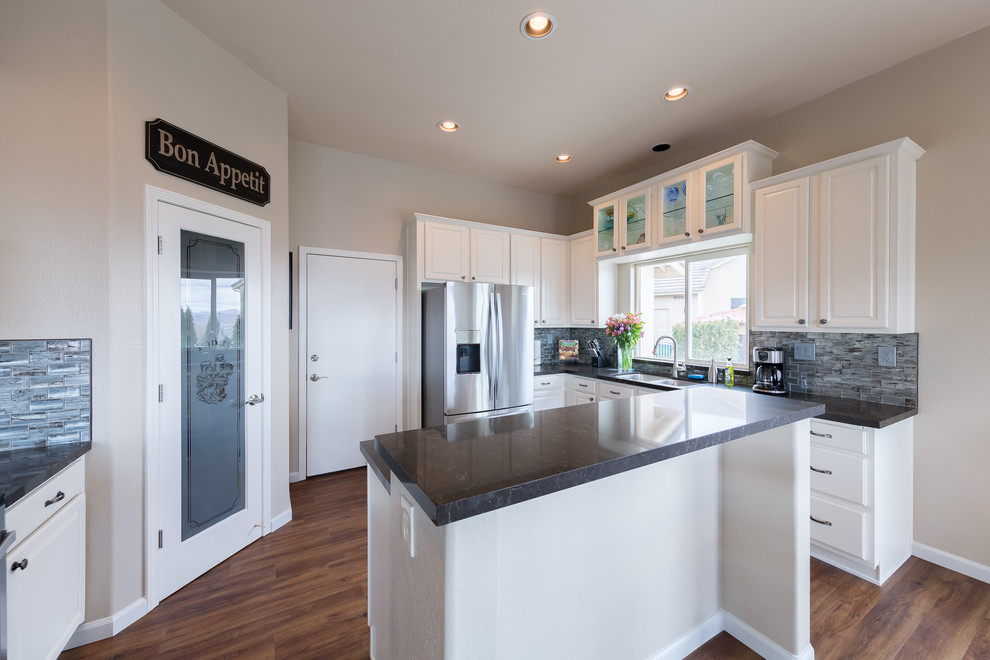 Inspiration for a mid-sized transitional u-shaped eat-in kitchen remodel with a single-bowl sink, raised-panel cabinets, white cabinets, quartzite countertops, gray backsplash, glass tile backsplash, stainless steel appliances and an island