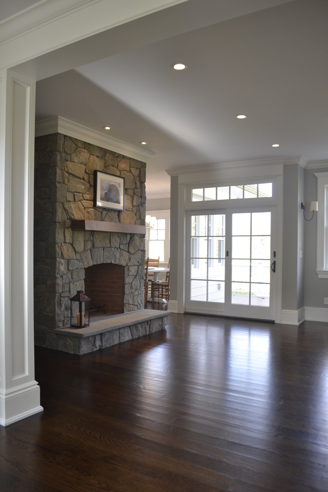 Photo of a large traditional open concept family room in New York with grey walls, dark hardwood floors, a standard fireplace, a stone fireplace surround and a built-in media wall.