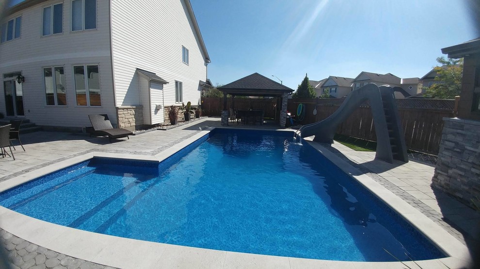 Inspiration for a mid-sized traditional backyard rectangular pool in Ottawa with a water slide and concrete pavers.
