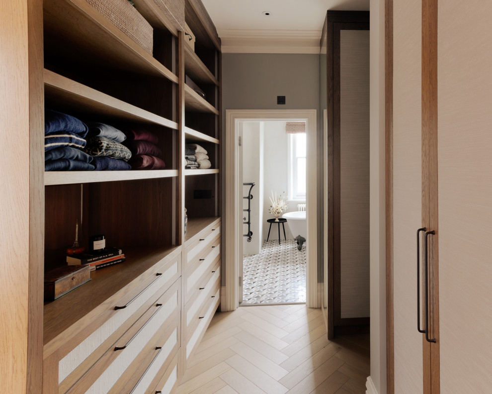 Design ideas for a mid-sized contemporary gender-neutral dressing room in London with recessed-panel cabinets, medium wood cabinets, medium hardwood floors, beige floor and coffered.