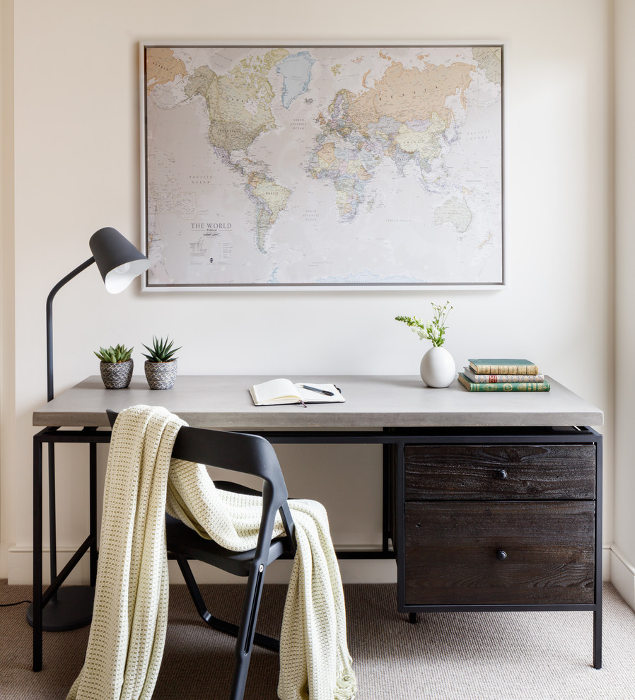 This is an example of a mid-sized contemporary home office in London with beige walls, carpet, a freestanding desk and grey floor.