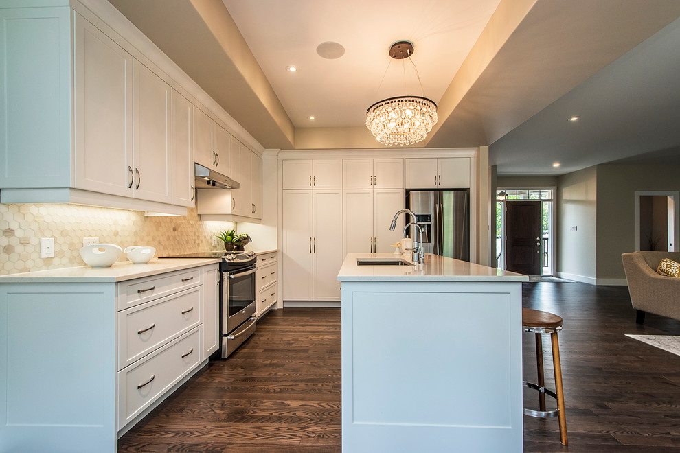 Example of a large transitional l-shaped dark wood floor open concept kitchen design with a double-bowl sink, shaker cabinets, white cabinets, quartzite countertops, beige backsplash, porcelain backsplash, stainless steel appliances and an island