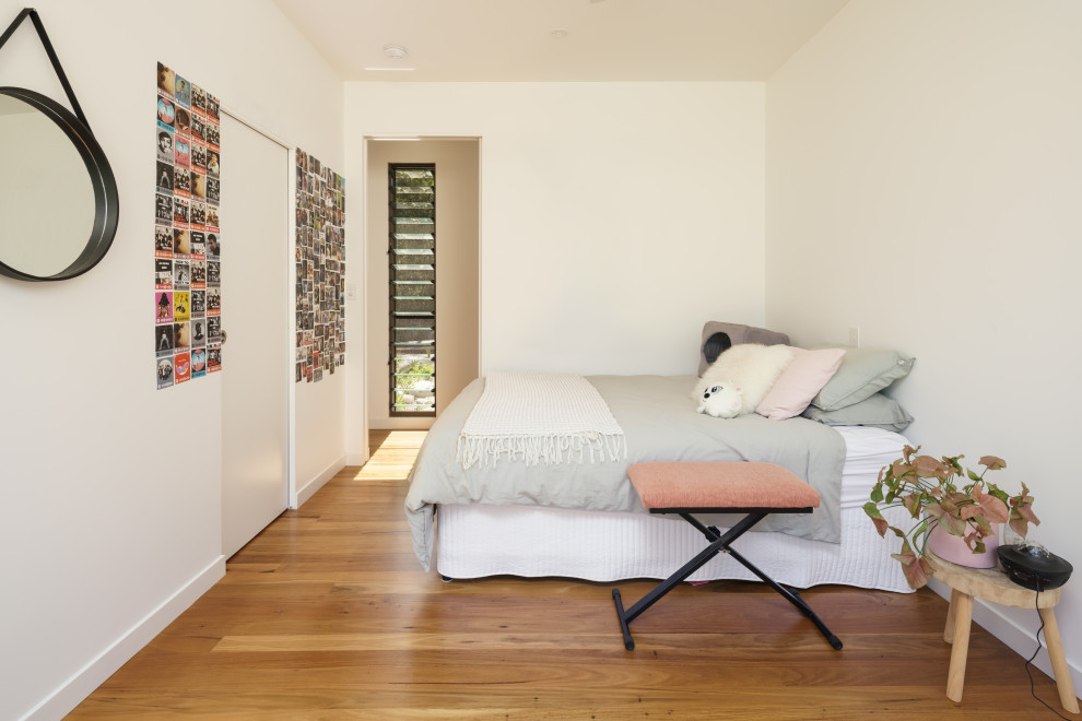Foto på ett funkis sovrum, med vita väggar, mellanmörkt trägolv och brunt golv