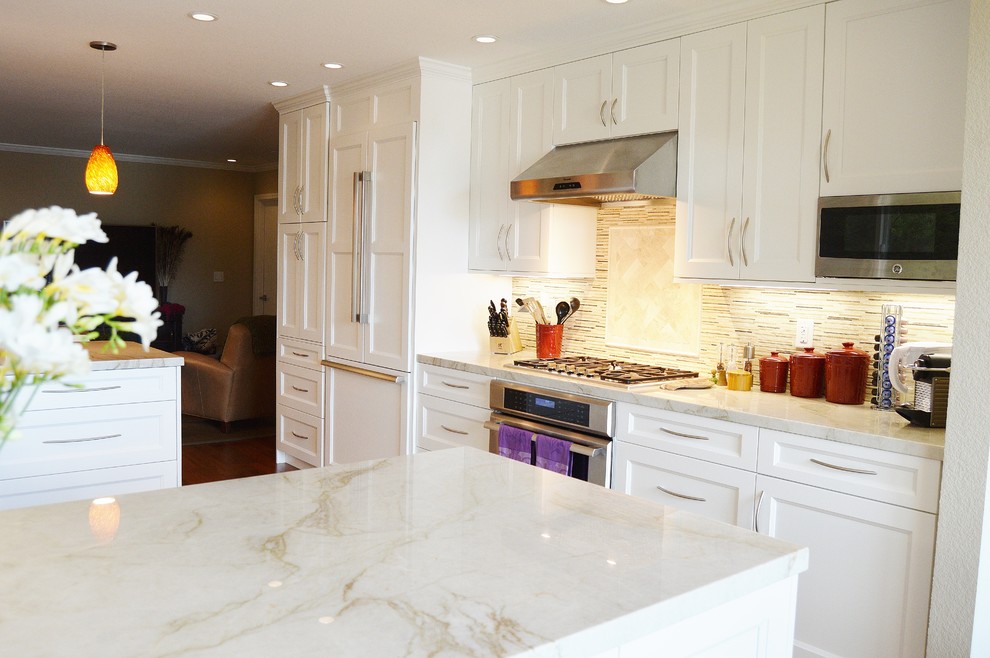 Inspiration for a mid-sized transitional u-shaped eat-in kitchen in San Francisco with an undermount sink, recessed-panel cabinets, white cabinets, quartzite benchtops, beige splashback, mosaic tile splashback, panelled appliances, medium hardwood floors and a peninsula.