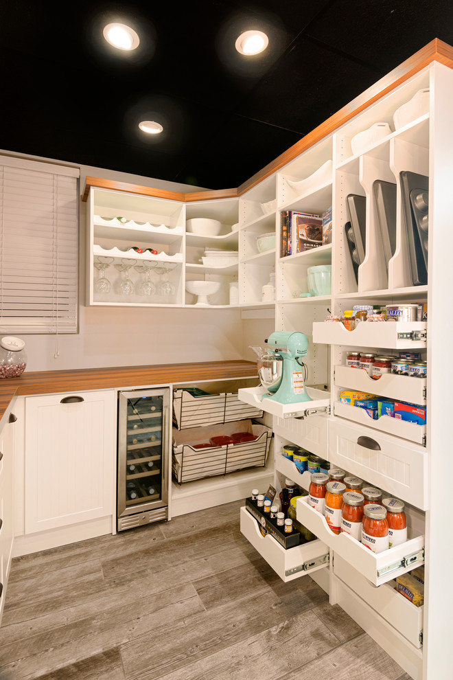 Photo of a mid-sized country kitchen pantry in Other with open cabinets, white cabinets, wood benchtops, porcelain floors, brown floor and brown benchtop.