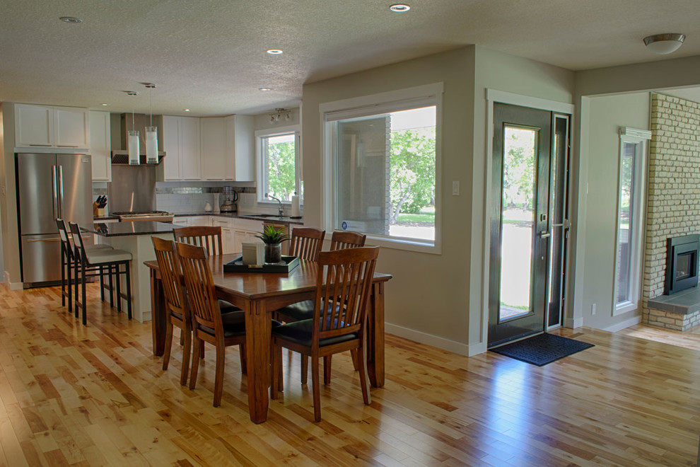 Small transitional l-shaped light wood floor and beige floor eat-in kitchen photo in Calgary with a double-bowl sink, shaker cabinets, white cabinets, white backsplash, subway tile backsplash, stainless steel appliances and an island