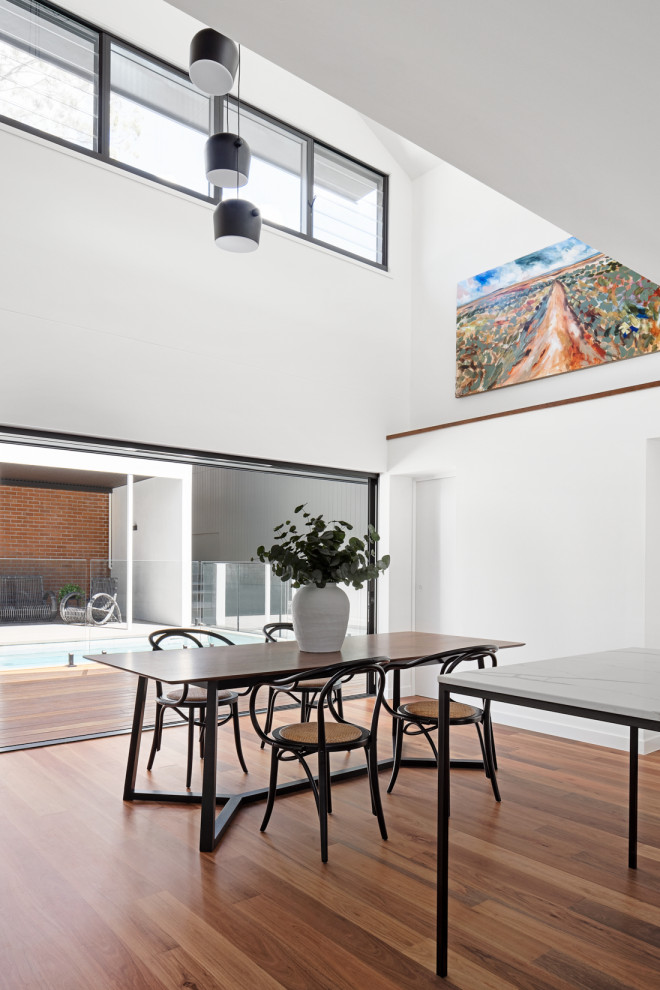 Design ideas for a contemporary dining room in Brisbane with white walls, medium hardwood floors and brown floor.