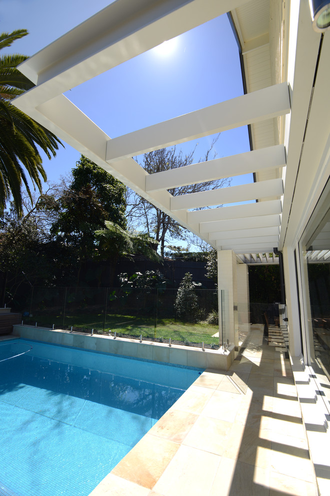 This is an example of a mid-sized contemporary backyard custom-shaped lap pool in Sydney with natural stone pavers.