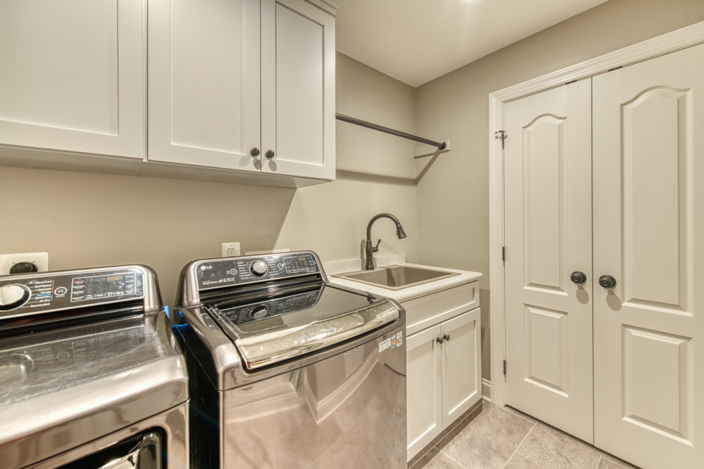 Inspiration for a mid-sized transitional galley utility room in DC Metro with shaker cabinets, white cabinets, quartz benchtops, beige walls, ceramic floors and a side-by-side washer and dryer.