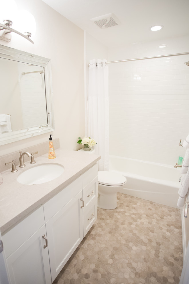 Small transitional master bathroom in Salt Lake City with shaker cabinets, white cabinets, a shower/bathtub combo, white tile, limestone, beige walls, an undermount sink, an alcove tub, a two-piece toilet, mosaic tile floors, soapstone benchtops, beige floor and a shower curtain.