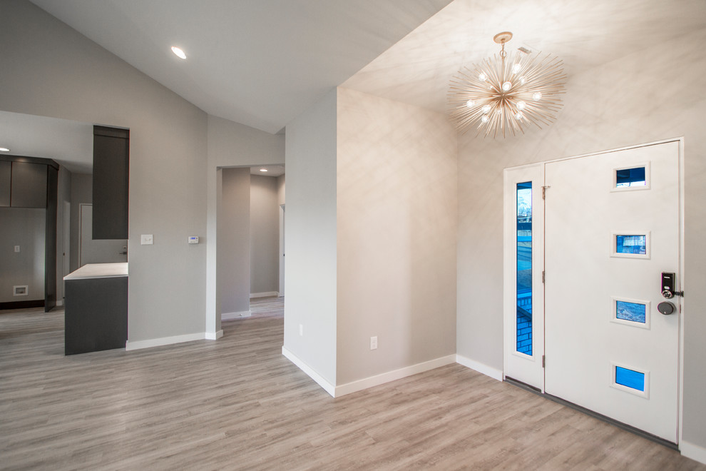 This is an example of a mid-sized contemporary entryway in Little Rock with beige walls, light hardwood floors, a single front door, a white front door and brown floor.