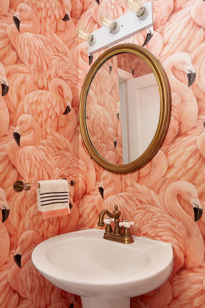 This is an example of a small eclectic powder room in Philadelphia with a one-piece toilet, pink walls and a pedestal sink.