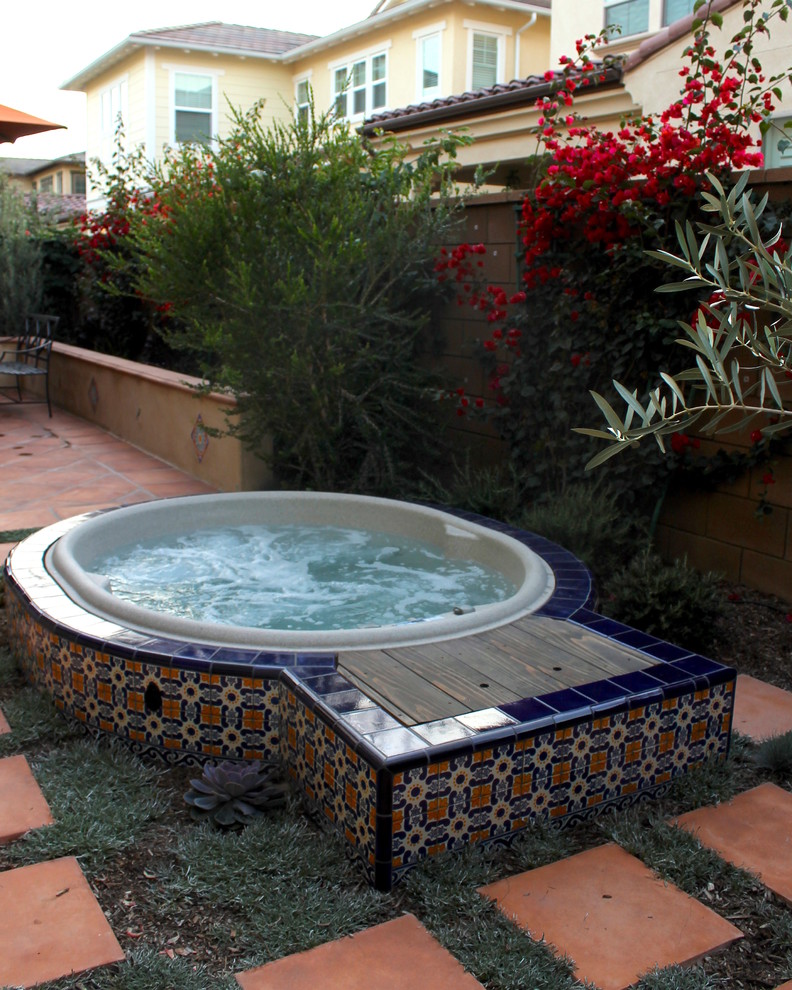 Mid-sized mediterranean backyard round pool in Orange County with a hot tub and tile.