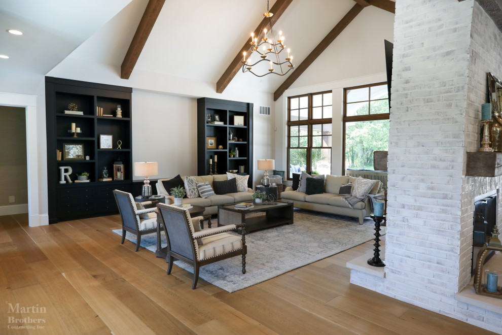 Large country formal open concept living room in Other with white walls, light hardwood floors, a two-sided fireplace, a brick fireplace surround, a wall-mounted tv and vaulted.