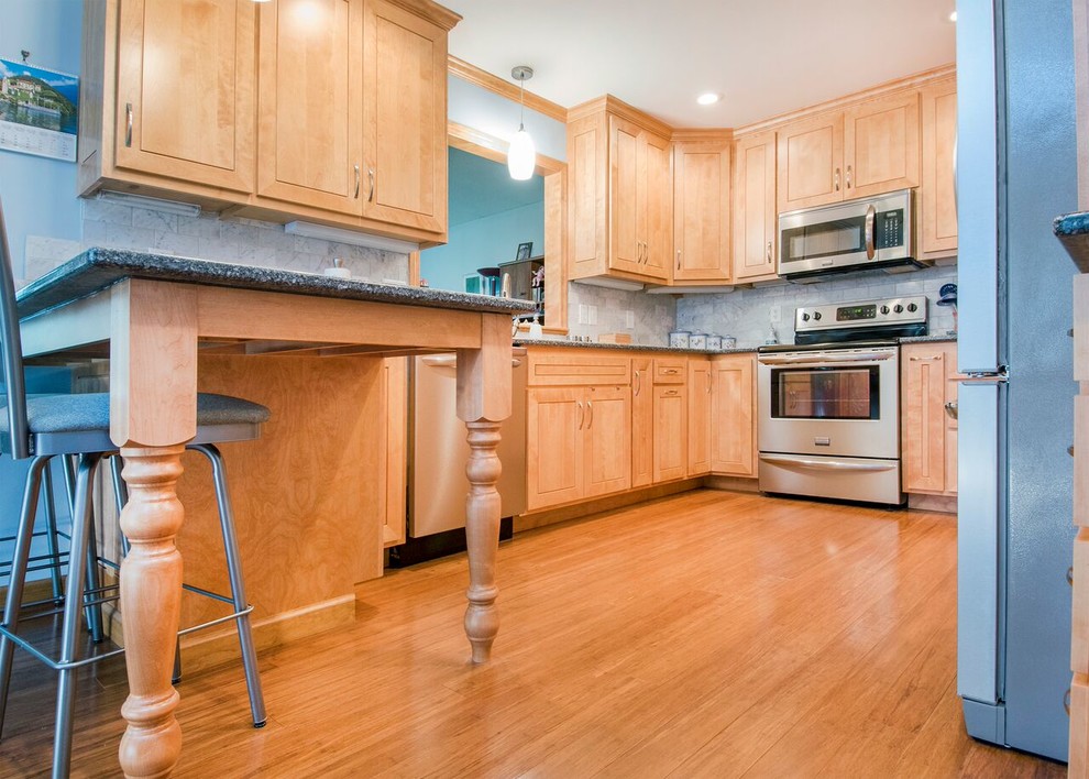 Mid-sized transitional u-shaped bamboo floor and brown floor enclosed kitchen photo in Cincinnati with a double-bowl sink, shaker cabinets, light wood cabinets, granite countertops, gray backsplash, marble backsplash, stainless steel appliances, a peninsula and gray countertops