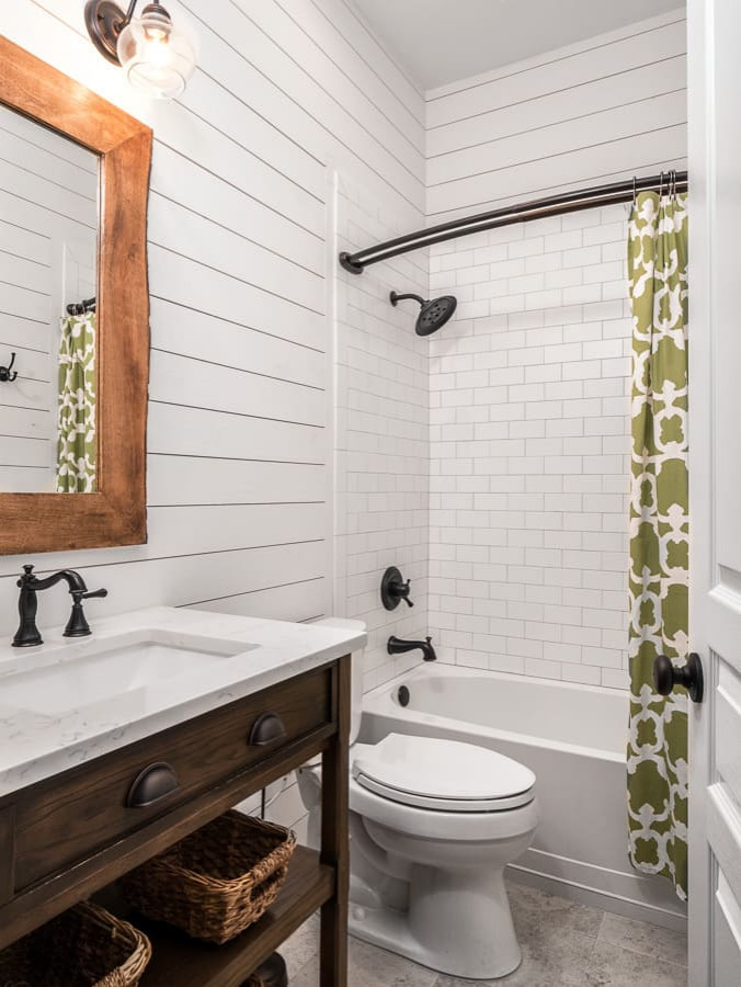Exempel på ett litet lantligt vit vitt badrum med dusch, med vita skåp, ett platsbyggt badkar, en dusch/badkar-kombination, en toalettstol med hel cisternkåpa, vit kakel, vita väggar, vinylgolv, ett nedsänkt handfat, marmorbänkskiva, grått golv och dusch med duschdraperi