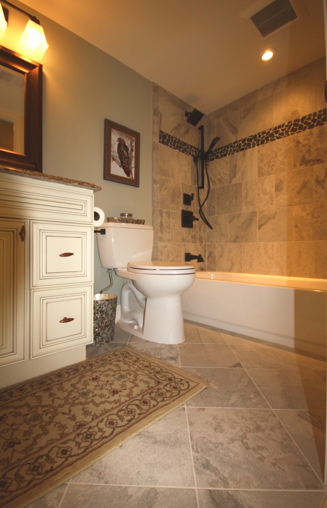 This is an example of a small transitional 3/4 bathroom in DC Metro with raised-panel cabinets, white cabinets, an alcove tub, a shower/bathtub combo, a two-piece toilet, gray tile, stone tile, blue walls, travertine floors, an undermount sink and granite benchtops.