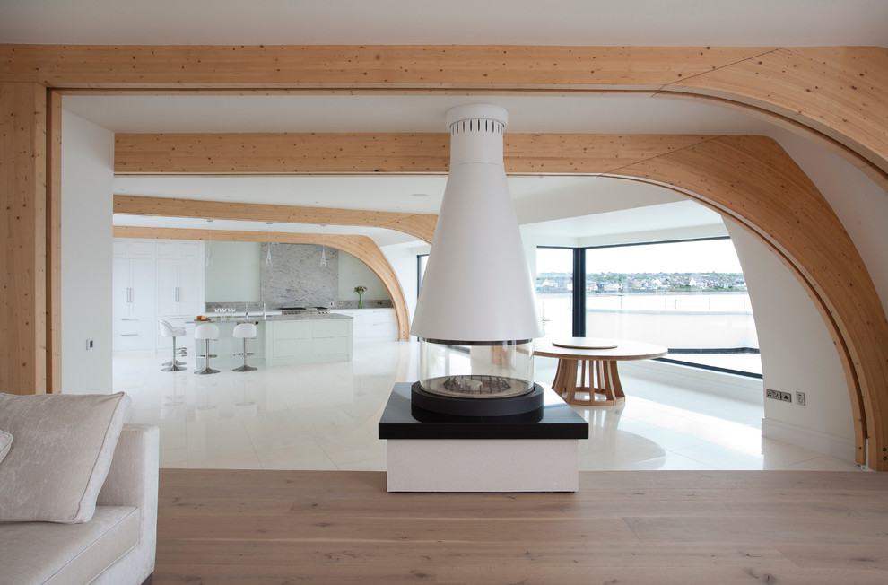Design ideas for an expansive beach style formal open plan living room in Dublin with white walls, light hardwood flooring, a hanging fireplace, a plastered fireplace surround and a concealed tv.