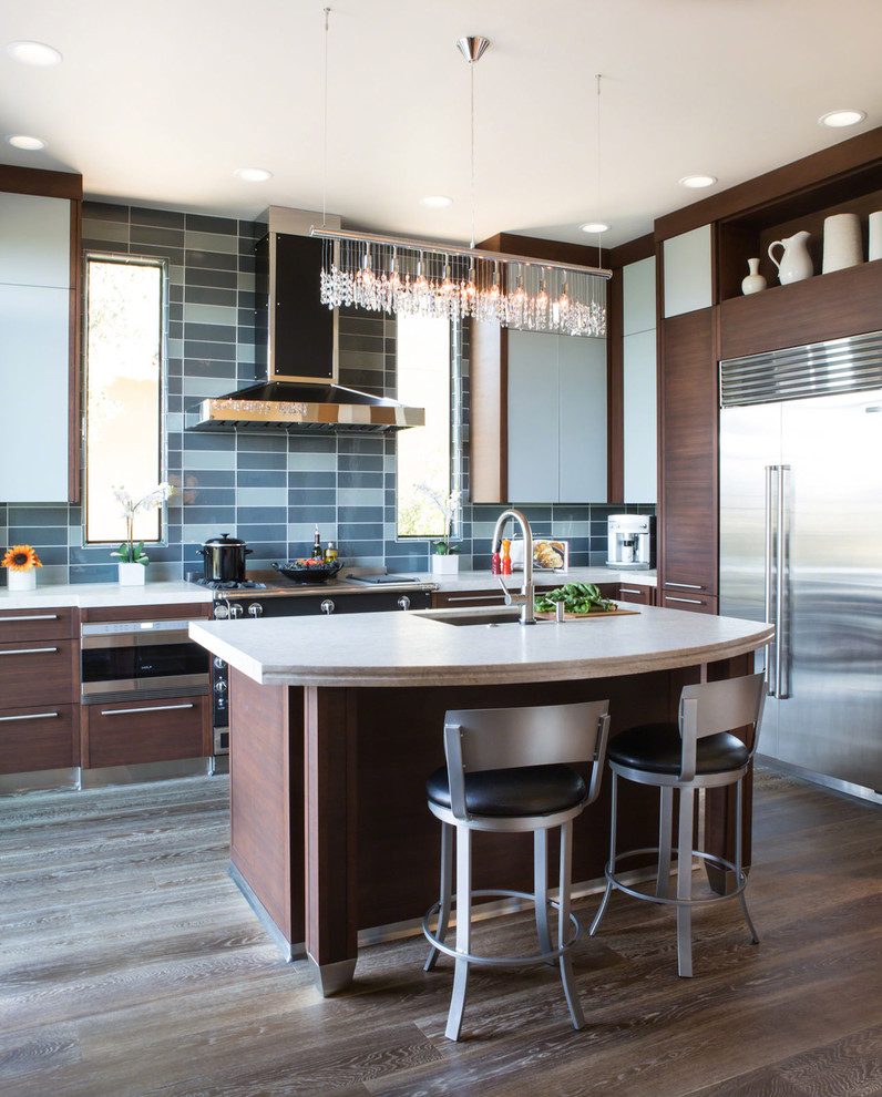 Photo of a contemporary l-shaped kitchen in Los Angeles with an undermount sink, dark wood cabinets, blue splashback, glass tile splashback, stainless steel appliances, dark hardwood floors, with island, brown floor and beige benchtop.